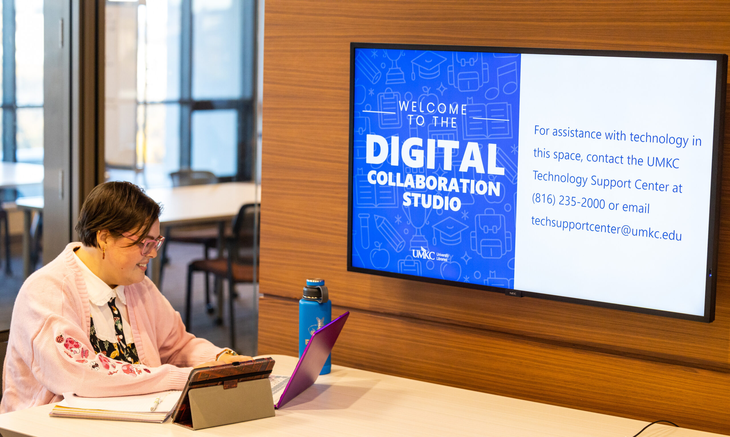 Student working beside digital display that reads Digital Collaboration Studio